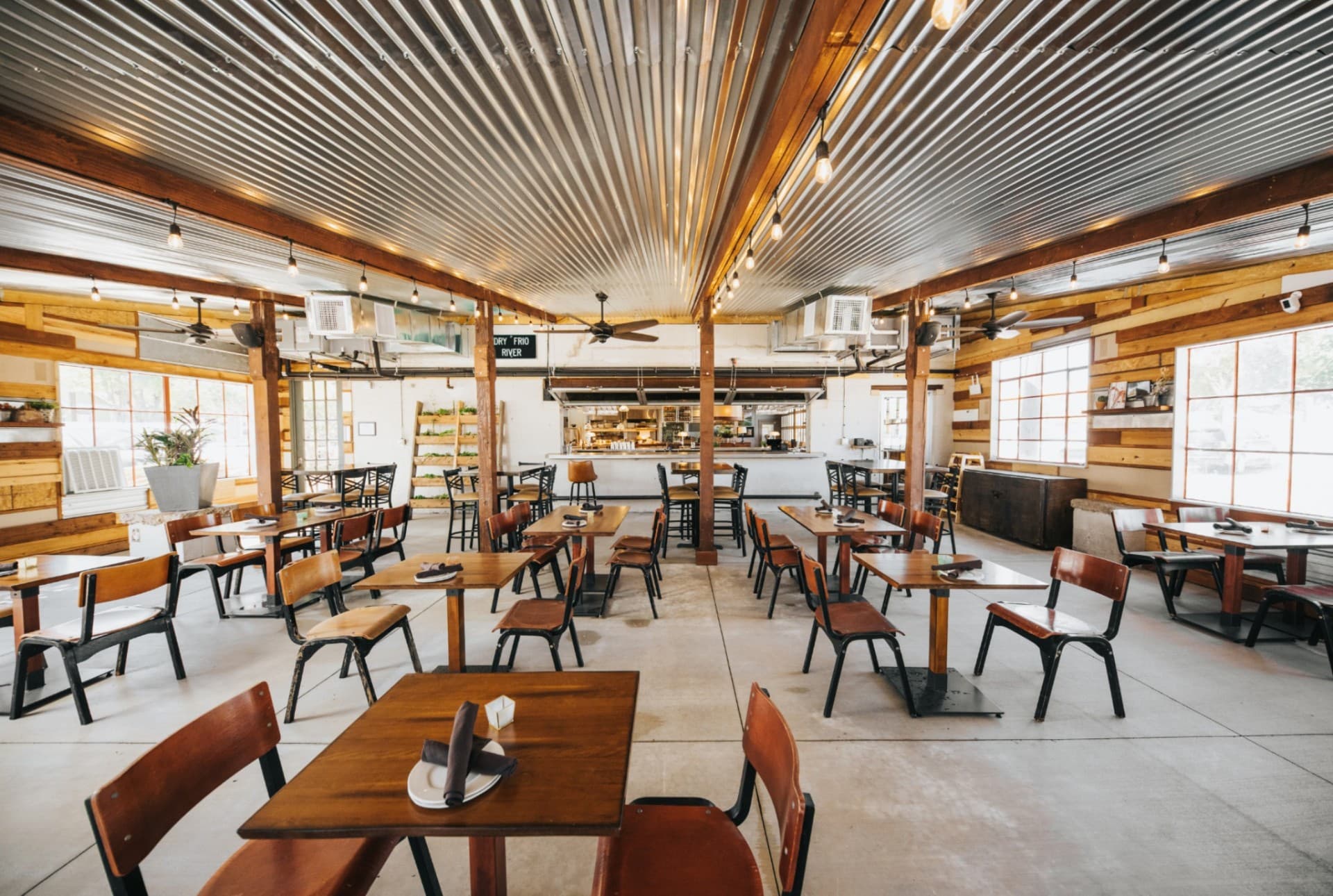 Encina restaurant wide dining room view with rustic wood and metal ceiling