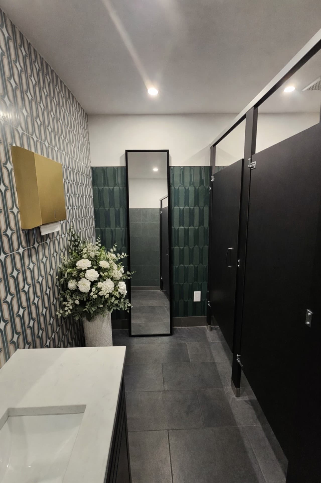 Prego Pasta House restroom wide view with stalls and green tile accent wall